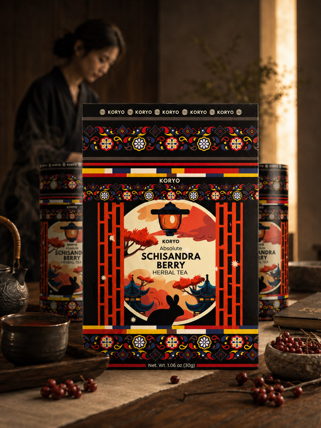 KORYO Schisandra Berry Herbal Tea box and cylindrical packages featuring the final Korean-inspired identity, displayed with tea, berries, and a woman in a warm interior.