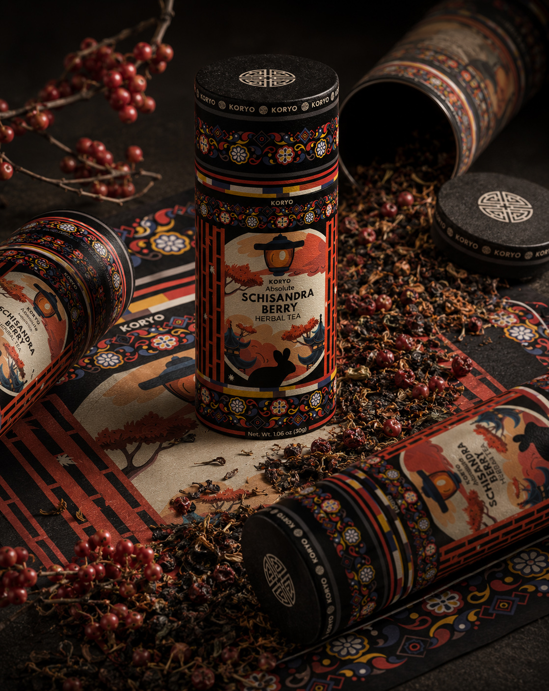 Complete KORYO Schisandra Berry Herbal Tea packaging system with cylindrical canisters, Korean-inspired ornamental artwork, loose herbal tea, and red berries.