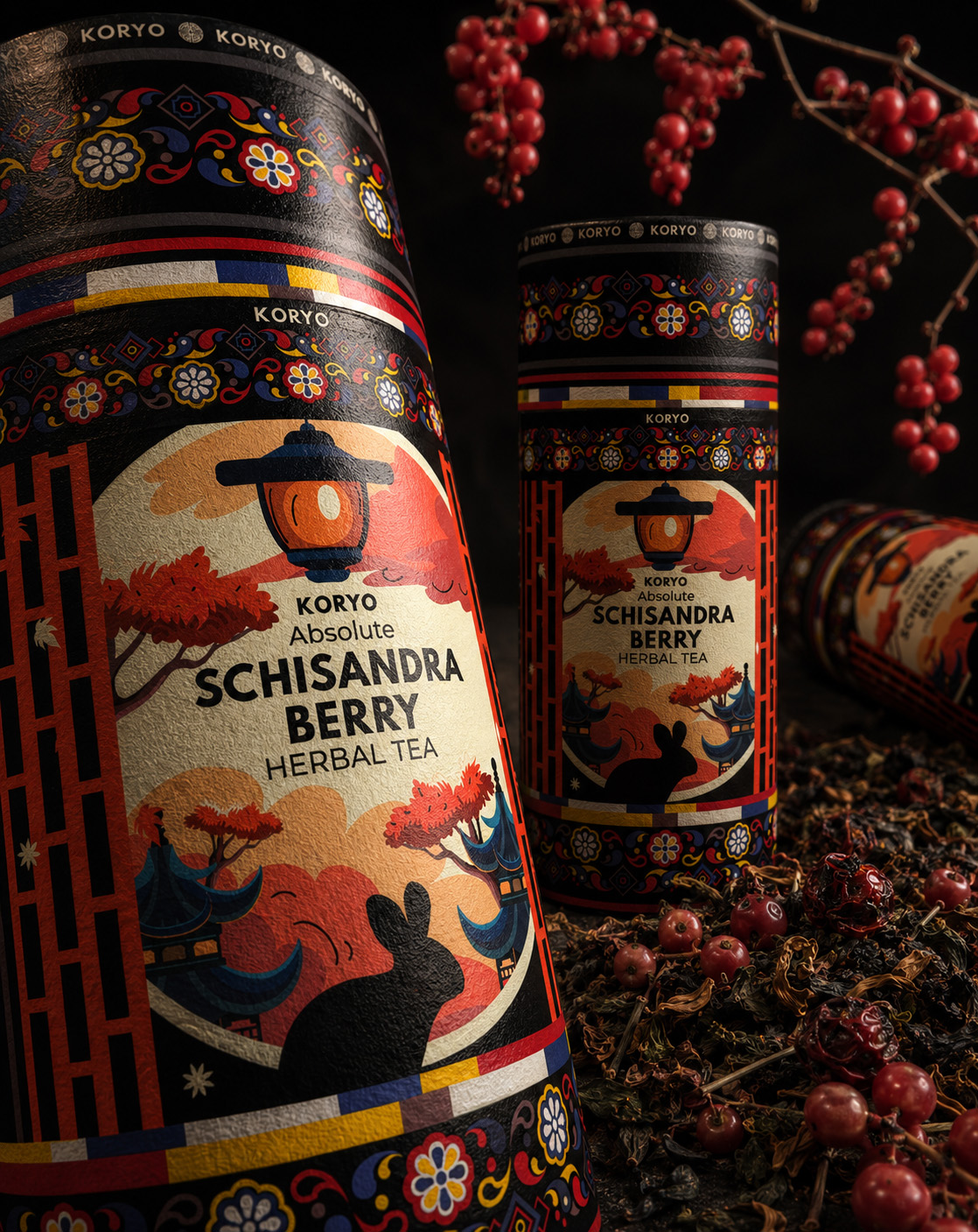 Close-up of final KORYO Schisandra Berry Herbal Tea canisters with Korean-inspired ornament, lantern artwork, loose tea, and red berries.
