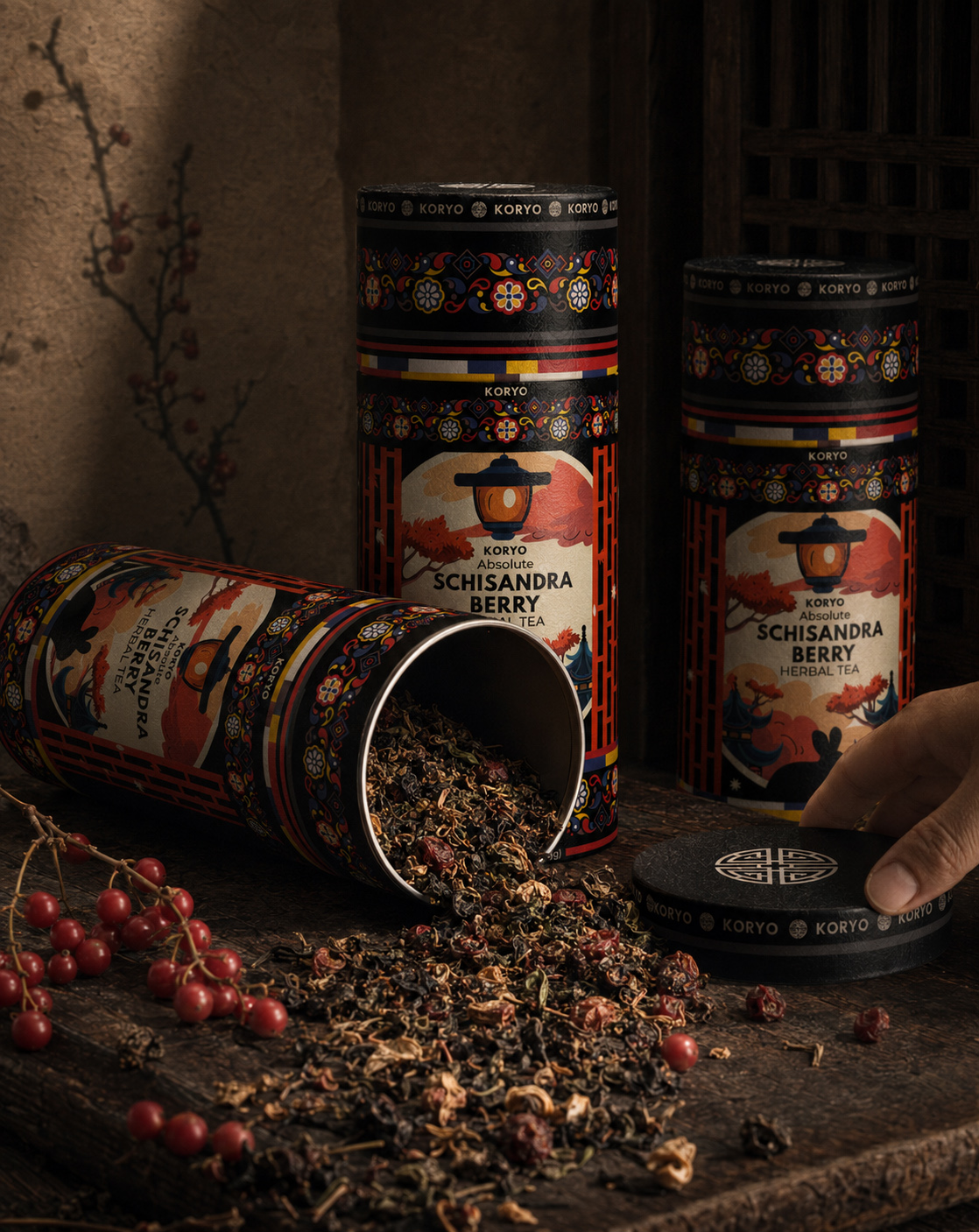 KORYO Schisandra Berry Herbal Tea canisters with loose herbal tea and berries as a hand lifts the decorated package lid.