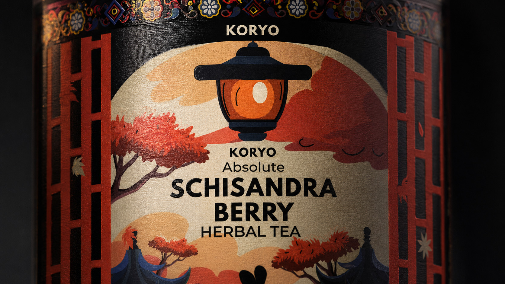 Macro view of the KORYO Absolute Schisandra Berry Herbal Tea front label showing the lantern illustration, product typography, architectural framing, and textured print surface.