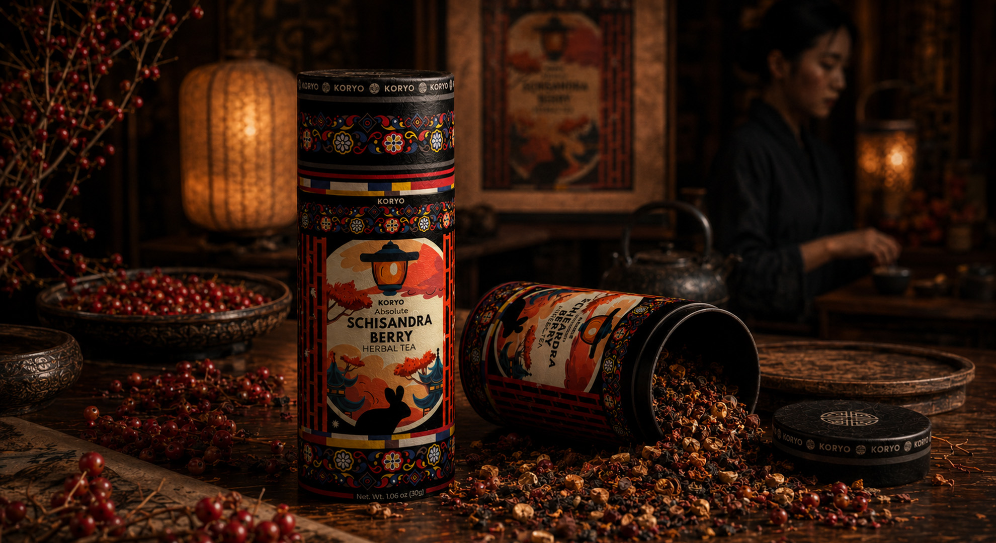 KORYO Schisandra Berry Herbal Tea canisters with loose tea and red berries while a woman prepares tea in the softly focused background.