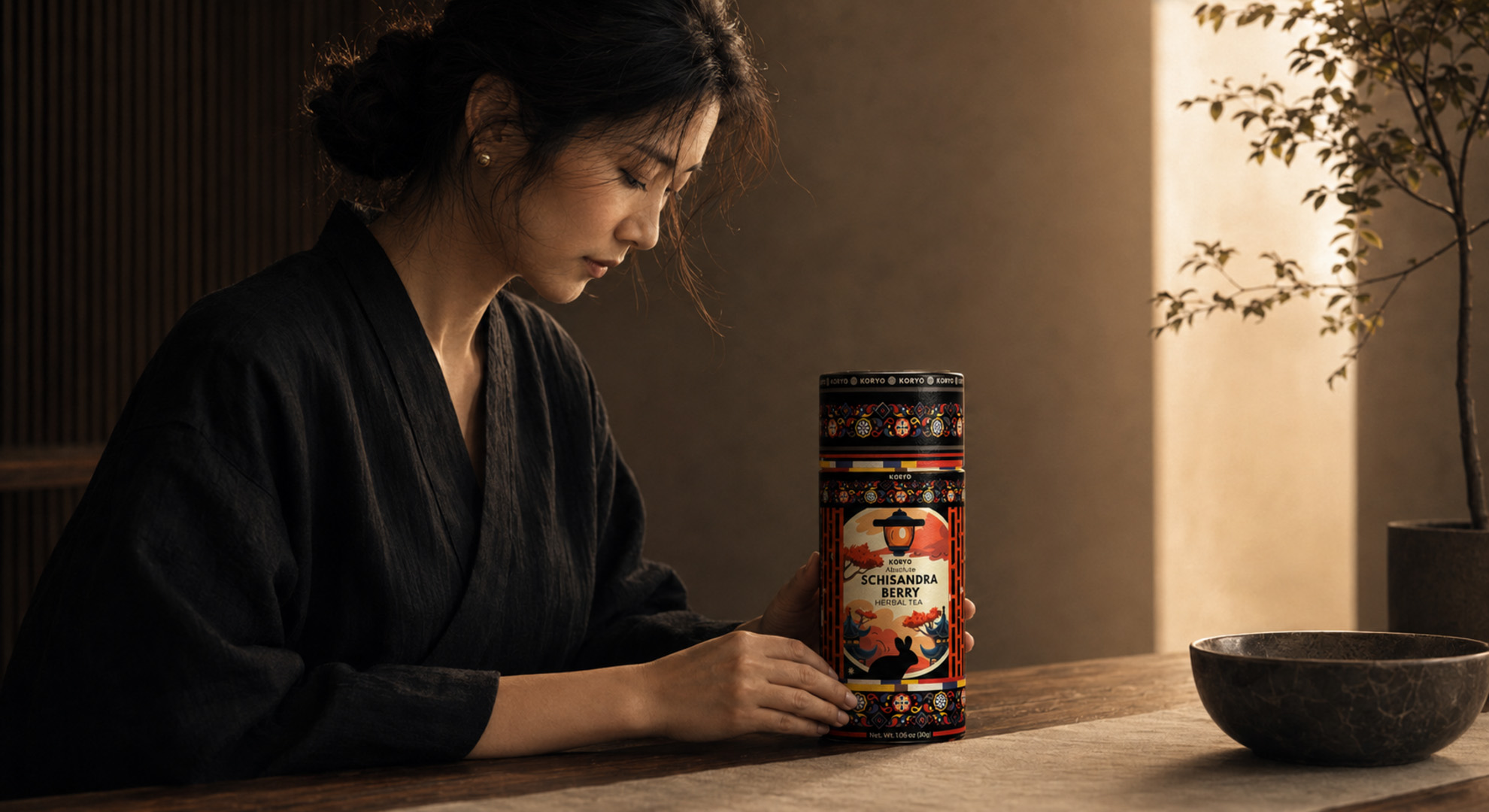 Woman carefully positioning a KORYO Absolute Schisandra Berry Herbal Tea canister on a wooden table in warm natural light.